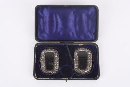 A pair of early 19th century cut steel and leather shoe buckles, with hinged fittings and elastic,