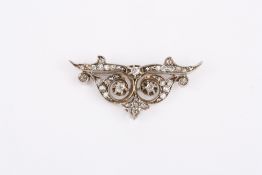 An Art Nouveau white metal and diamond brooch, with scrolled foliate decoration in unmarked white