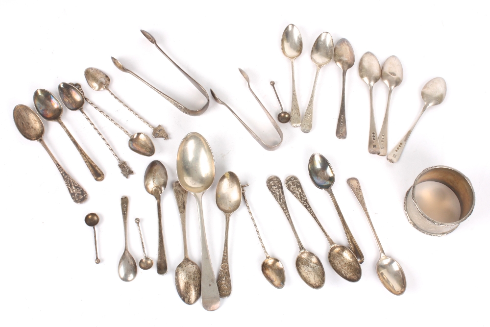 A collection of assorted silver spoons, predominantly teaspoons, together with sugar tongs and a