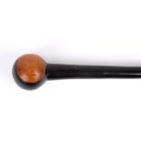 A carved wooden cosh, the tapered ebony shaft terminating in a carved wooden pommel, length 89cm .