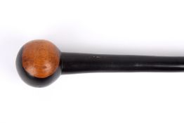 A carved wooden cosh, the tapered ebony shaft terminating in a carved wooden pommel, length 89cm .