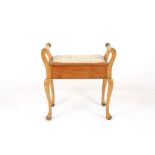 An Edwardian piano stool, with scrolled arms, padded rising seat and supported on cabriole legs,
