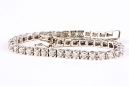 A 14k white gold and diamond line bracelet, comprising 44 tension set brilliant cut diamonds of