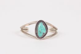 A turquoise and silver coloured metal stiff bangle, the turquoise mounted within rope-shaped
