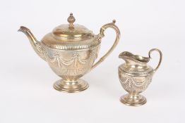 A Victorian Adam design silver teapot and matching cream jug, hallmarked London 1880, the body