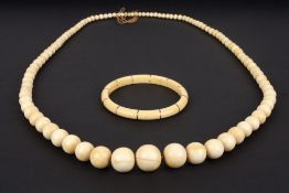An early 20th century graduated ivory bead necklace, circa 1920, together with a banded stiff