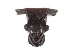 A carved oak figure of a Cavalier’s head, probably 17th century underneath a 19th century shelf,