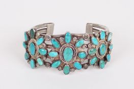A North American Indian turquoise and white metal stiff bangle, the open bangle decorated with
