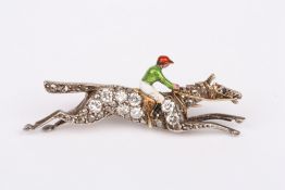 An Edwardian gold diamond and enamel jockey horse racing brooch, the jockey in brightly coloured