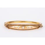 An Edwardian gold coloured metal stiff bangle
set with five graduated diamonds in gypsy setting with