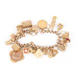 A 9ct gold belcher link charm bracelet
set with approximately 27 charms including a Victorian half