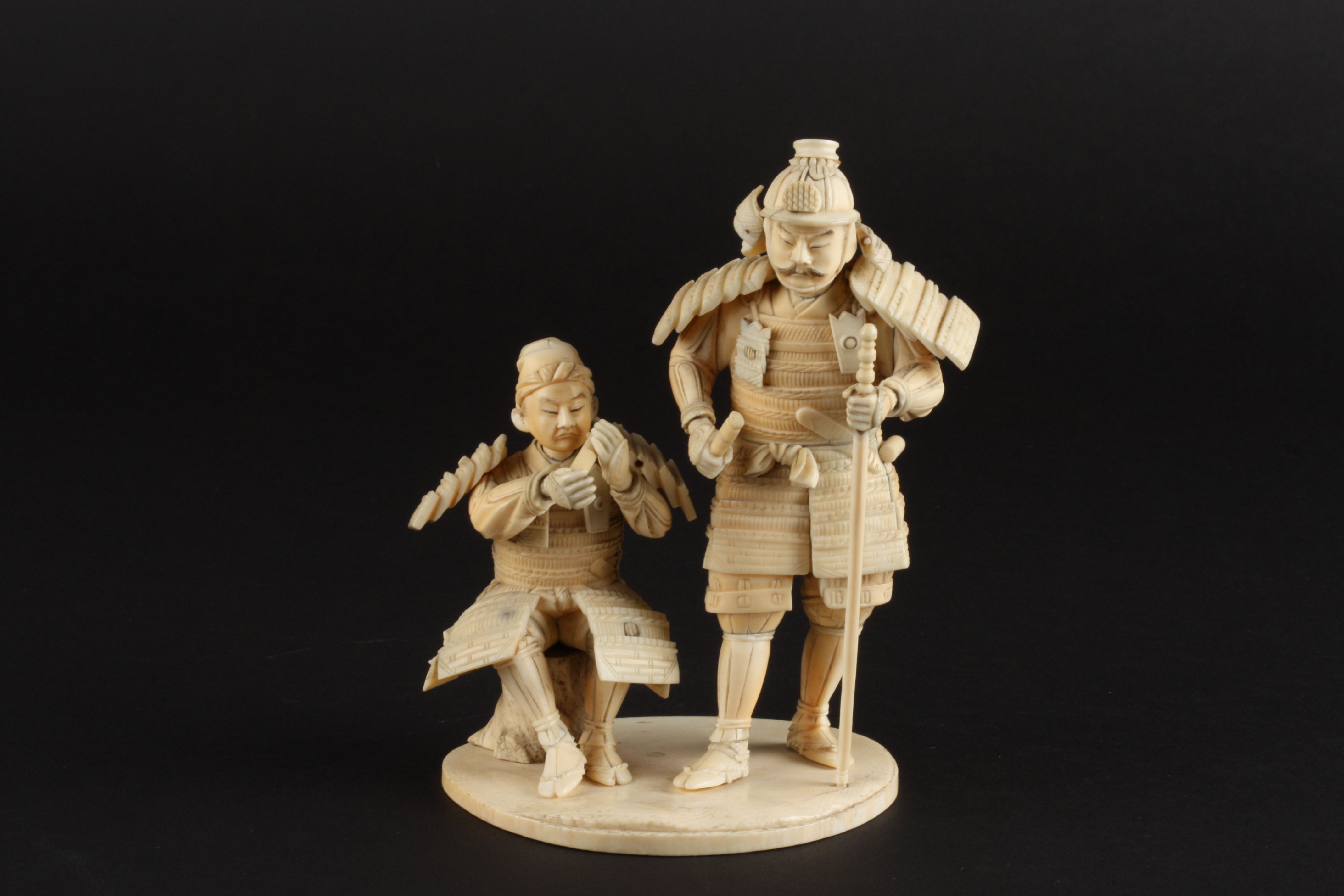 An ivory okimono figure group of two Japanese warriors
late 19th/early 20th century 
one of the