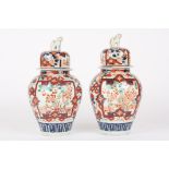 A pair of late 19th century Japanese Imari vases and covers
the lids crested with dogs of foe, the