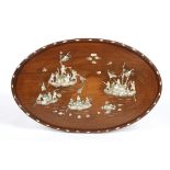 An oval wooden panel
inlaid with mother-of-pearl depicting Oriental figures on boats fighting amidst