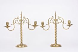 A large pair of brass candelabra, each with twin scrolled arms and circular sconces, supported on