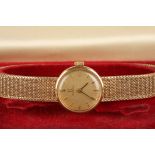 A 9ct gold ladies Omega wrist watch
the gilt dial with baton numerals, and a woven gold strap, in an