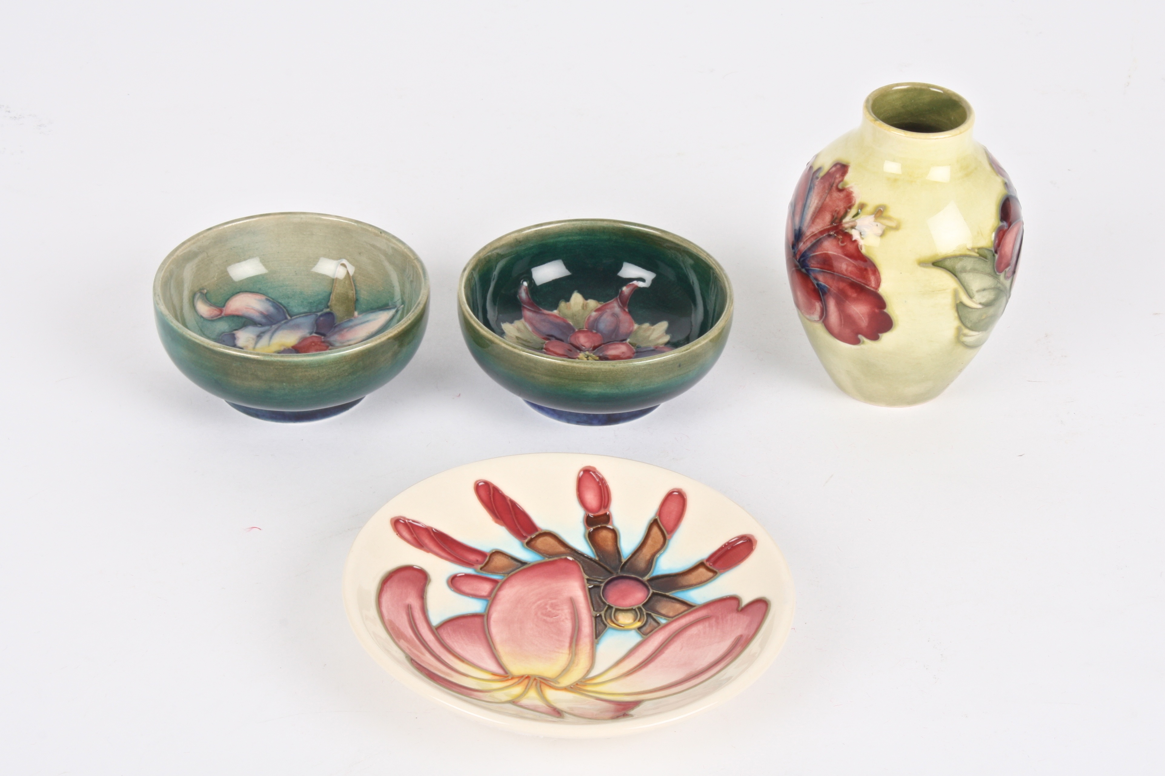 Four pieces of miniature Moorcroft
comprising a Hibiscus vase; a pair of small green ground floral