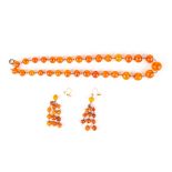 An amber coloured graduated bead necklace
together with a pair of amber coloured bead earrings.