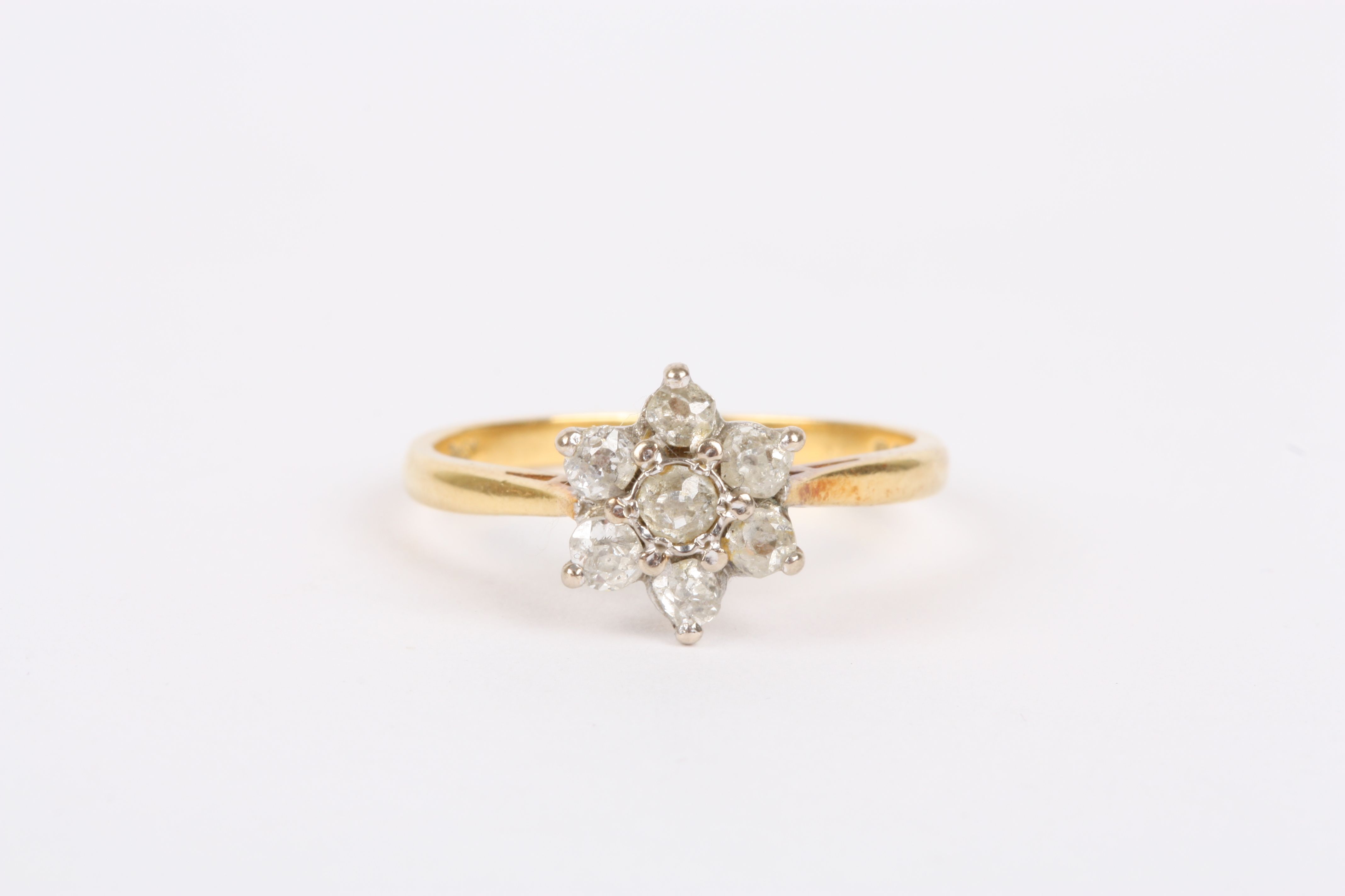 An 18ct gold and diamond ring
the diamond set in flower head, the central diamond set with six