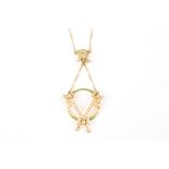 An Edwardian 15ct gold, seed pearl and green enamel pendant
formed as a trio of ribbons on a green