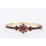 A Bohemian garnet stiff bangle 
the entire band set with garnets in claw setting on gold coloured