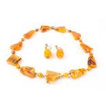 An early 20th century rough amber coloured necklace
together with a pair of amber coloured bead