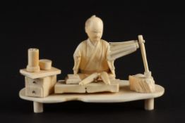 A Japanese ivory okimono figure of a gentleman seated at a work benchlate 19th/early 20th century