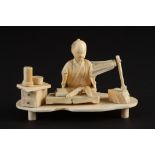 A Japanese ivory okimono figure of a gentleman seated at a work bench
late 19th/early 20th century