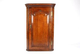 An 18th century oak corner cupboardthe top with moulded cornice over a single panel door door