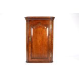 An 18th century oak corner cupboard
the top with moulded cornice over a single panel door door