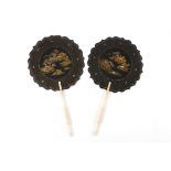 A pair of black lacquer Japanned fans
of shaped round paddle form decorated to the centre with