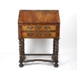 A 19th century walnut bureau on stand
the front lifting down to reveal a compartmented interior,