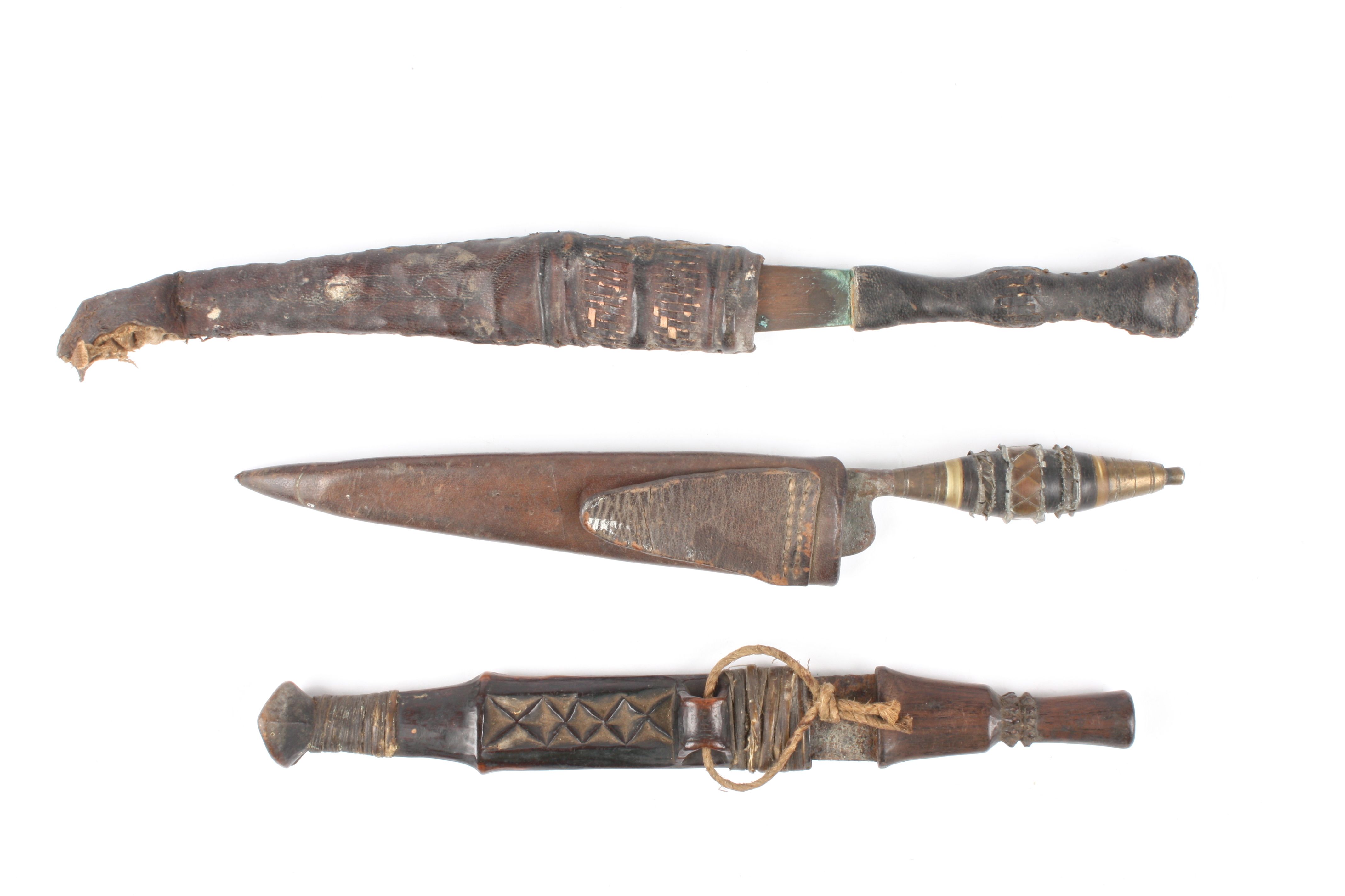 A group of three 19th century tribal daggers
two with leather scabbards, one with wooden