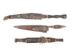 A group of three 19th century tribal daggerstwo with leather scabbards, one with wooden