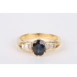 A sapphire and diamond ring
set with large central oval sapphire, flanked either side by three small
