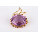 A Victorian amethyst oval brooch
set with large faceted amethyst, in a yellow metal six claw mount