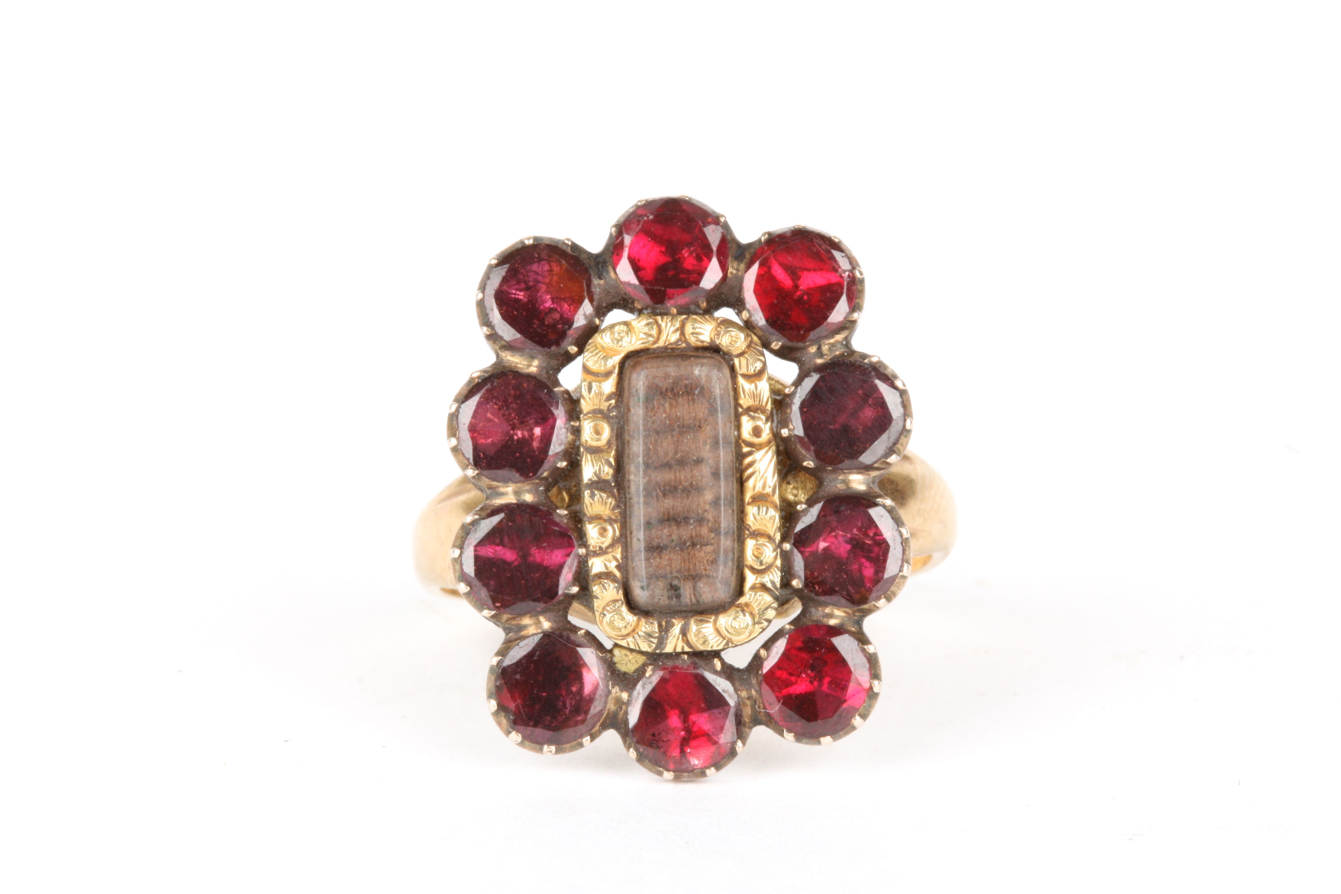 A gold and garnet mourning ring
set with a central panel of woven hair surrounded by ten faceted