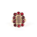 A gold and garnet mourning ring
set with a central panel of woven hair surrounded by ten faceted