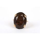 A large 9ct gold and smokey quartz dress ring set with large faceted oval stone in a bold four