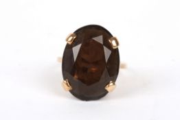 A large 9ct gold and smokey quartz dress ring set with large faceted oval stone in a bold four