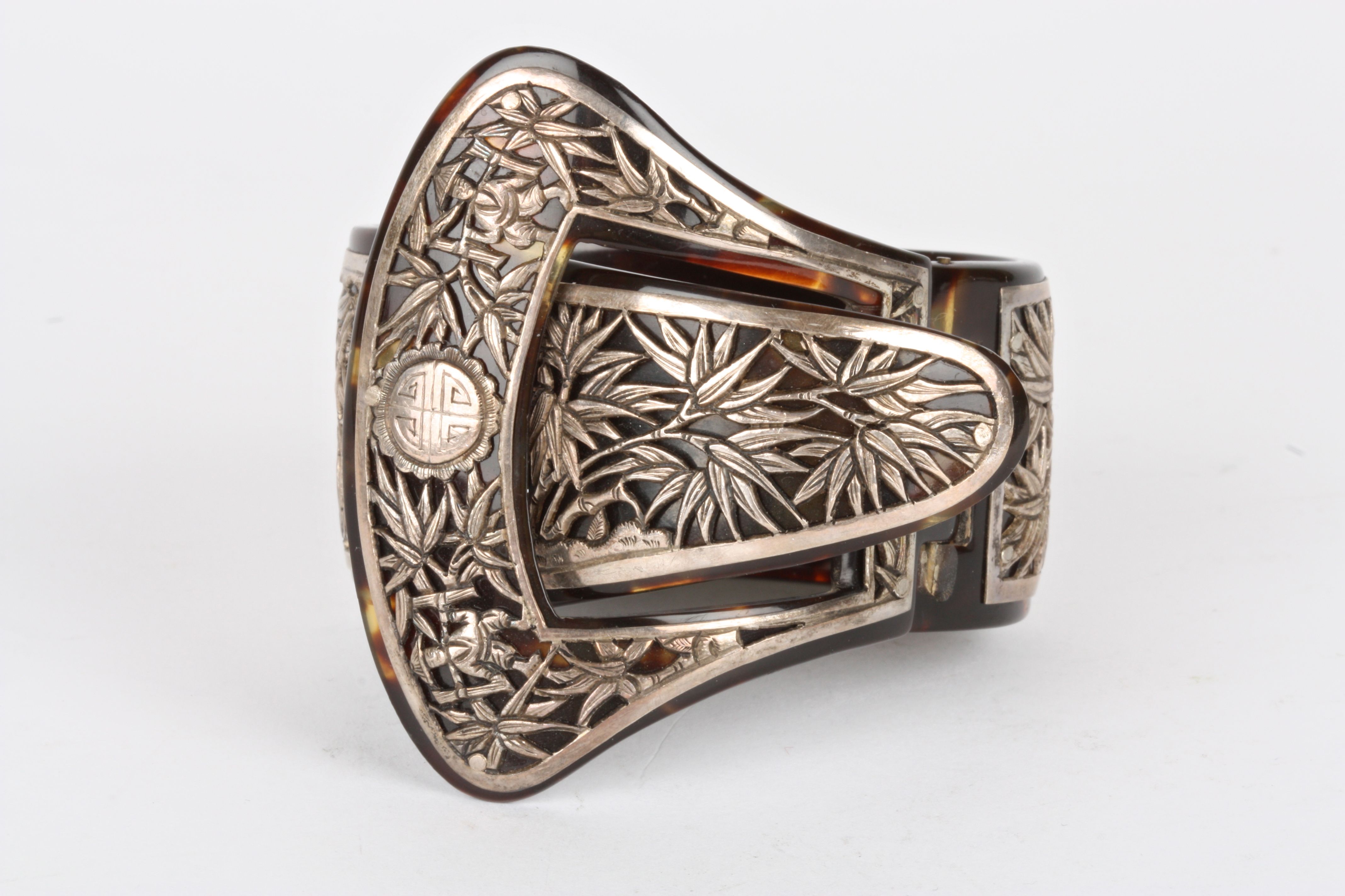 An early 20th century Oriental tortoiseshell and white metal bangle
with hinged clasp of buckle