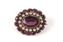 An amethyst colured glass and seed pearl oval cluster brooch set with large central oval amethyst