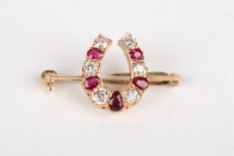 A ruby and diamond horse shoe broochwith alternating pear shaped rubies and circular diamonds,