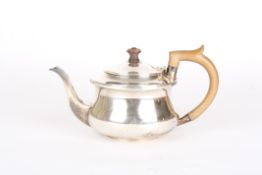 A George V bachelors silver teapot,hallmarked Birmingham 1925, of circular form with carved