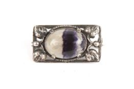 An Edwardian Art Nouveau silver and bluejohn broochthe oval stone set in a silver frame decorated