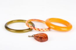 An amber pendanttogether with three bakelite stiff bangles (4), length of pendant 4.2cmCondition: