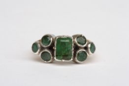 An Arts and Crafts ringset with central rough green stone, possibly emerald flanked by three