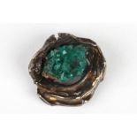 An unusual natural emerald crystal brooch
set in a naturalistic white metal mount, 3.5 cm wide.