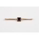 A 15ct gold and garnet bar brooch
set with square stone, the bar fronted with platinum, 5 cm long.