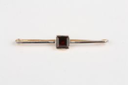 A 15ct gold and garnet bar broochset with square stone, the bar fronted with platinum, 5 cm long.